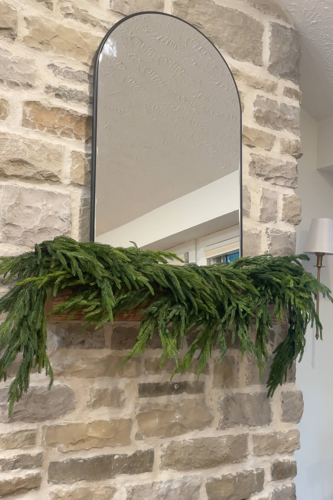 Hanging realistic pine garland on a fireplace mantel.